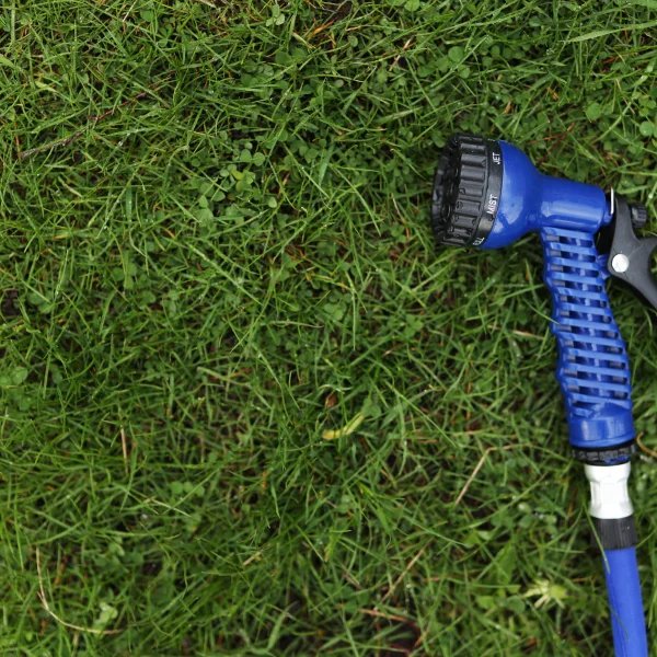 Un tuyau bleu avec une poignée noire posé sur l'herbe, utilisé par une compagnie de traitement de pelouse.
